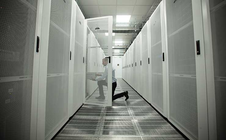 Inside the cold aisle of the data center at the Red Bull Racing Factory in Milton Keynes, United Kingdom. The three-across perforated floor tiles reflect the cooling density. (Image: Thomas Butler / Red Bull Content Pool) 